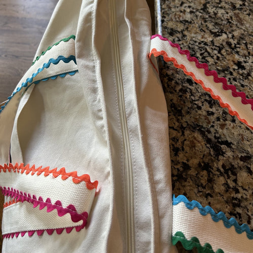 Close-up of a white mahjong tote bag  with colorful trim on a textured surface