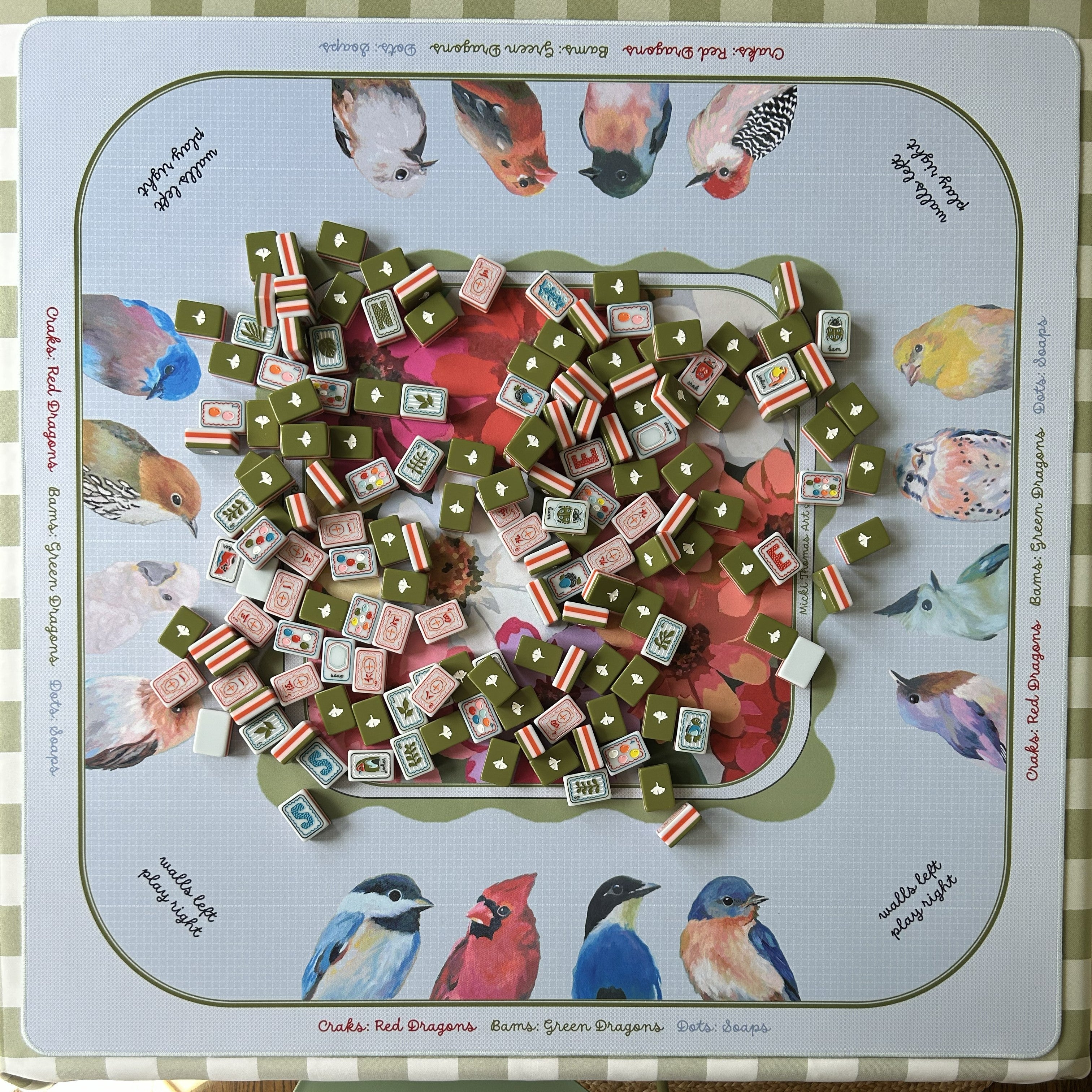 Mahjong mat with tiles and a colorful board featuring bird illustrations