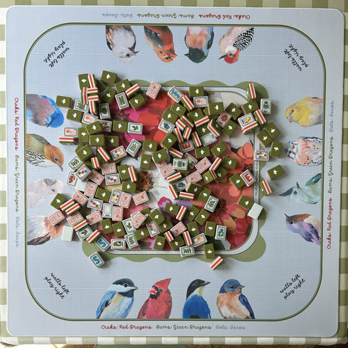 Mahjong mat with tiles and a colorful board featuring bird illustrations