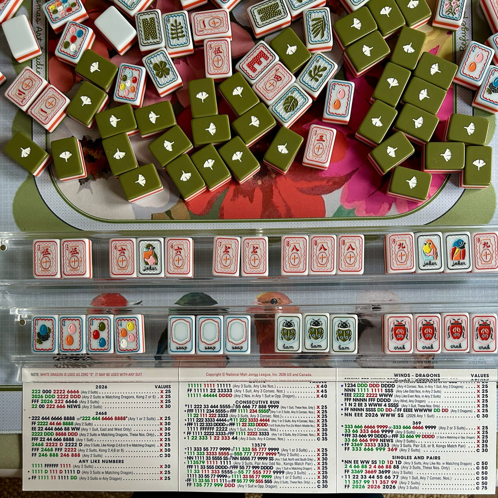 Close-up of a Mahjong game with tiles and score sheet.