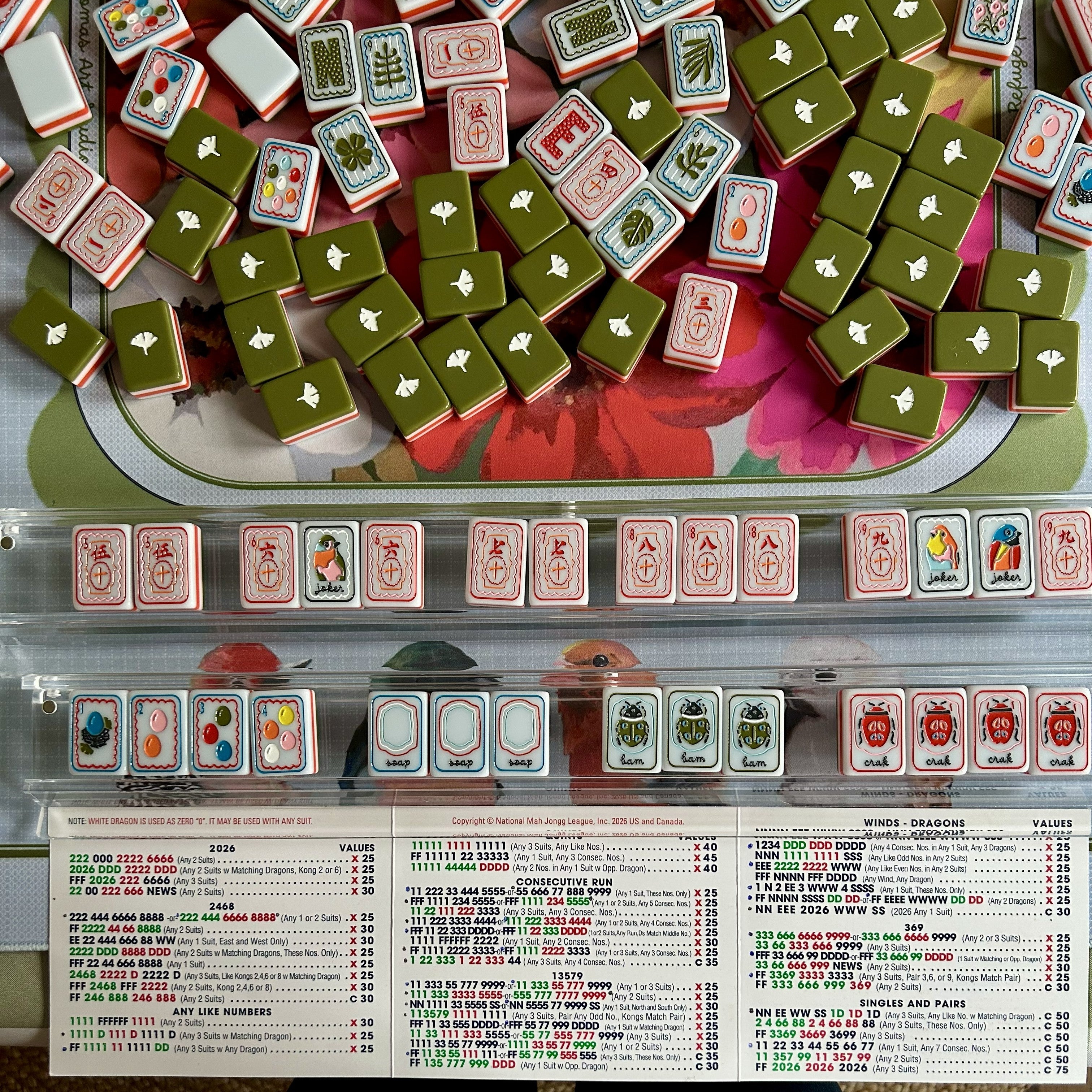 Close-up of a Mahjong game with tiles and score sheet.