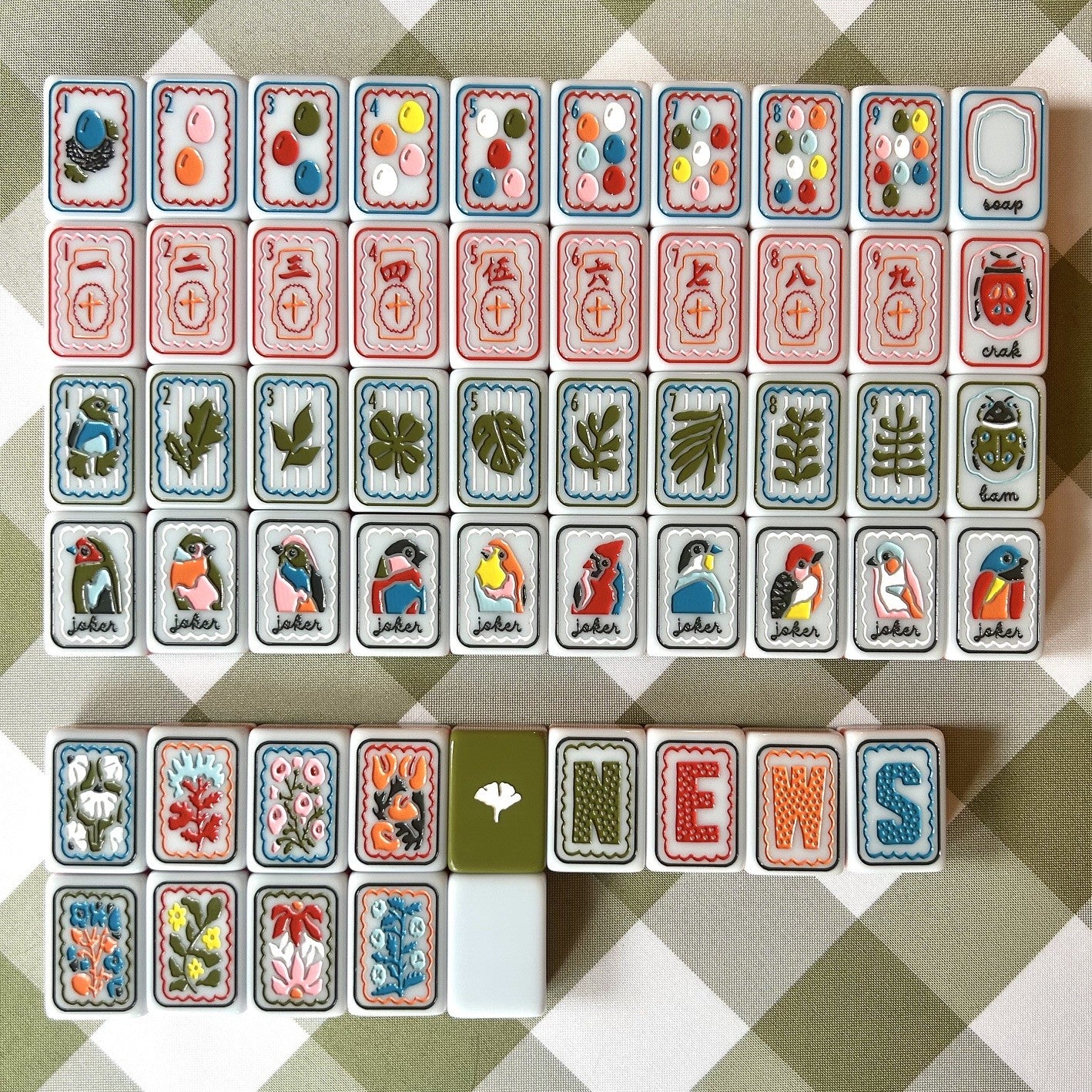 Collection of colorful Mahjong tiles with various symbols on a checkered background