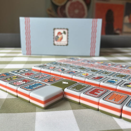 Set of Mahjong tiles on a checkered tablecloth with a box in the background